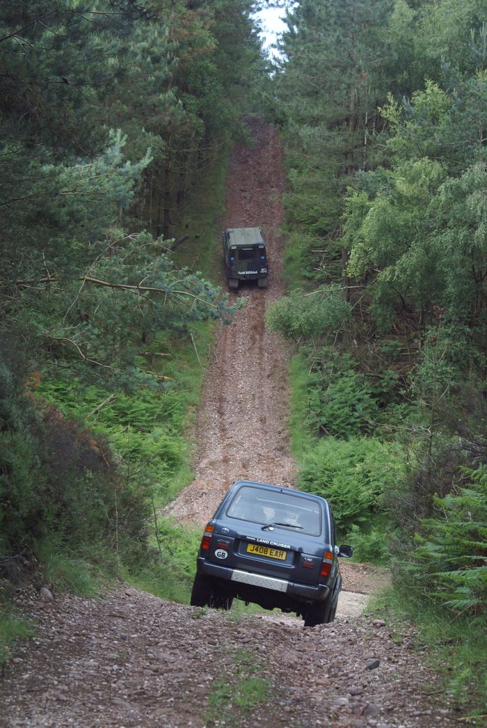 Two SUVs navigate a rugged forest track in England, showcasing off-road adventure.
