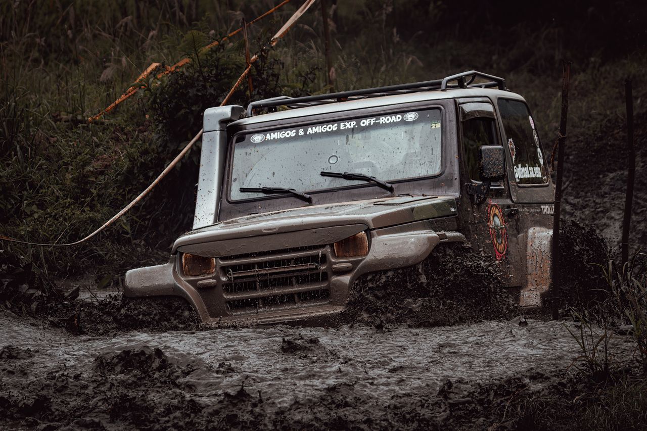 A rugged off-road vehicle tackles a challenging muddy path during an adventurous drive.