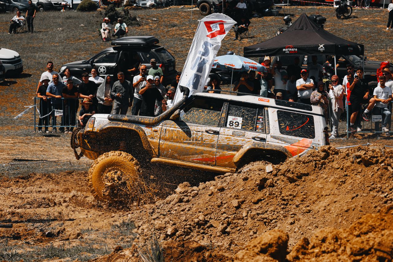 A thrilling moment in an off-road car race with spectators and flying mud, capturing the intensity and excitement.