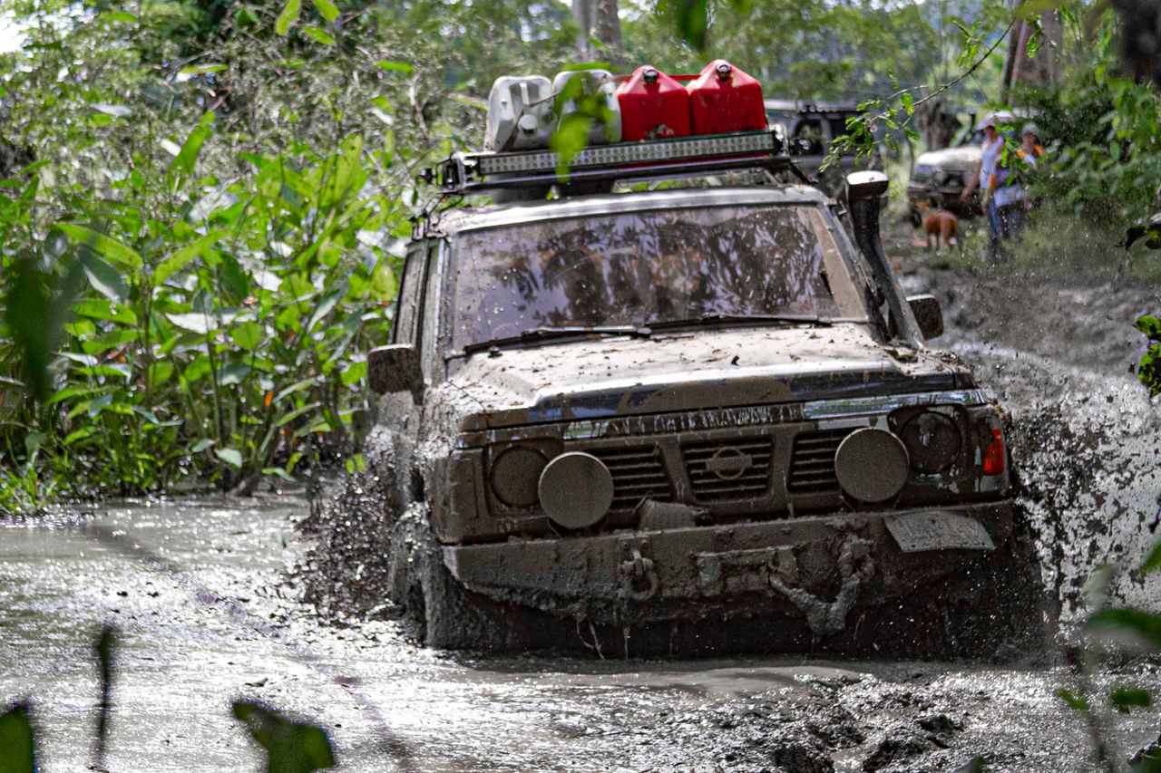 A 4x4 vehicle tackles a challenging muddy trail, showcasing off-road prowess.