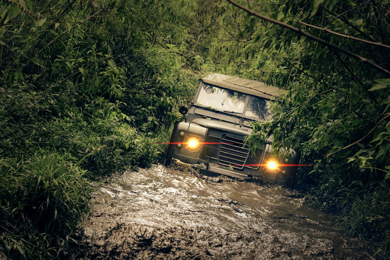 Jeep navigating through muddy jungle path, showcasing resilience and adventure.
